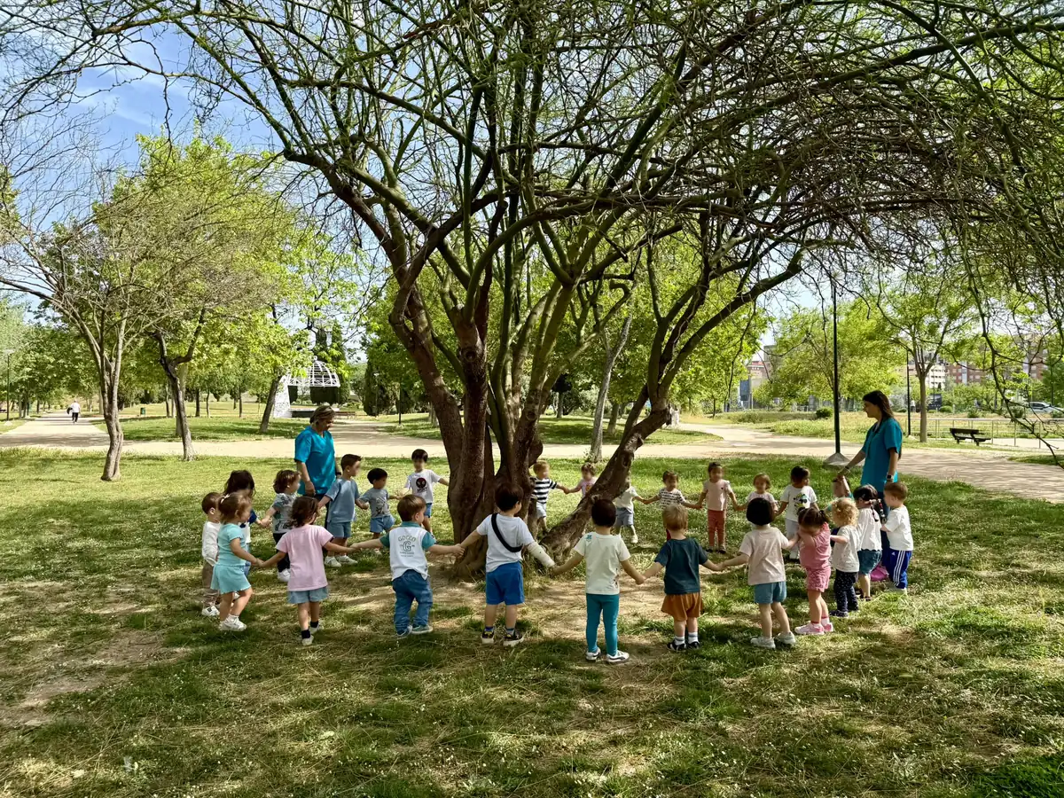 Aprendizaje vivencial en Guardería Panda: los peques en corro alrededor de un árbol en el parque